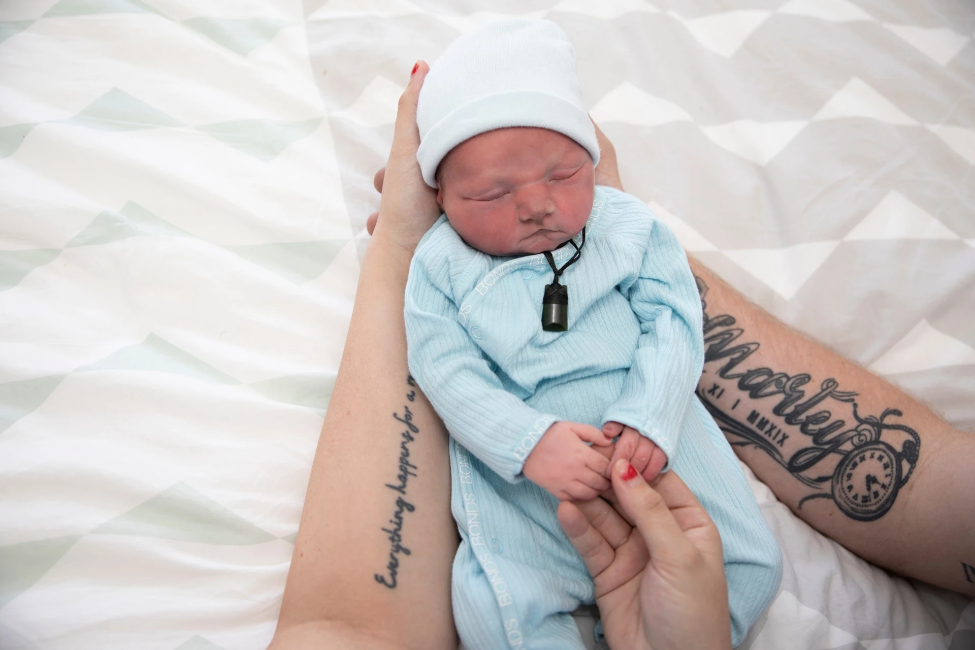 Jasper resting in loving hands, wearing a knitted hat and outfit
